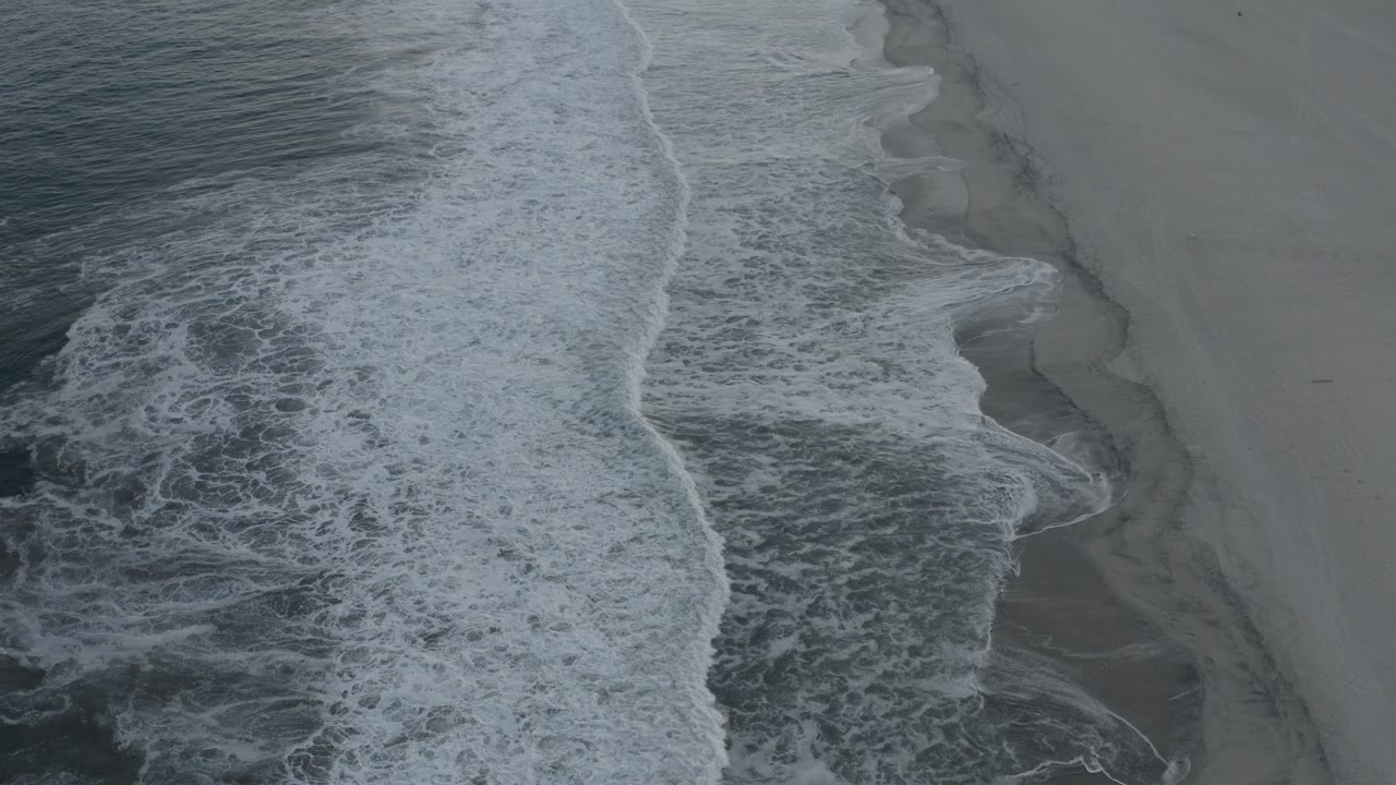 Overhead surf washing onto a wide empty beach.