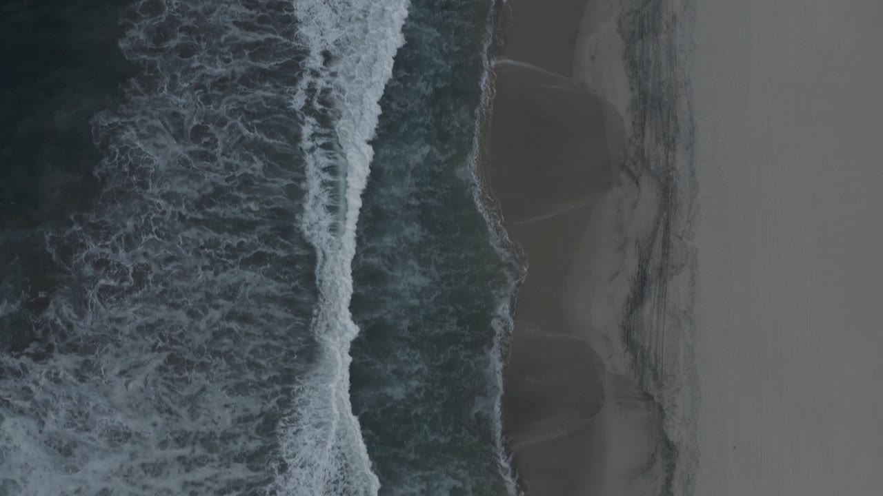 White surf breaking next to empty sand.