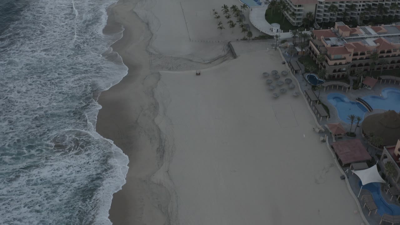 Aerial shoreline with stronger surf and beachfront condominium complex.