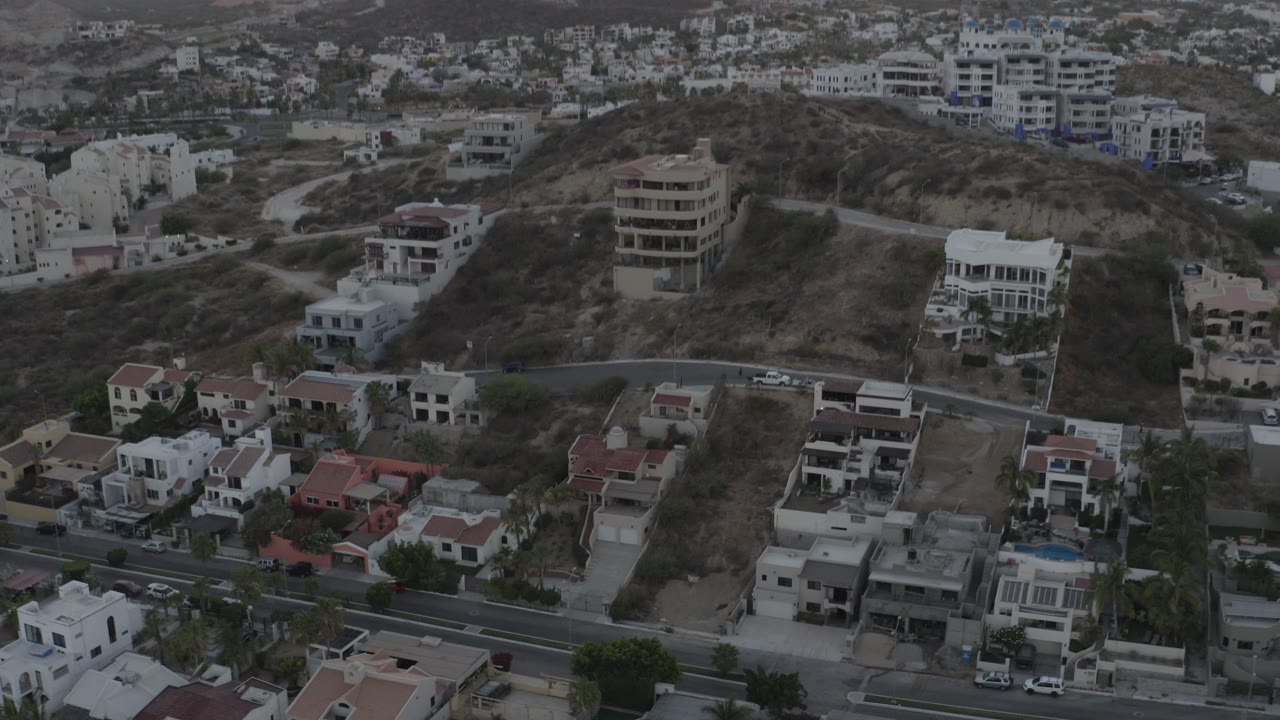 Overhead view of hillside homes, roads, and vacant lots.