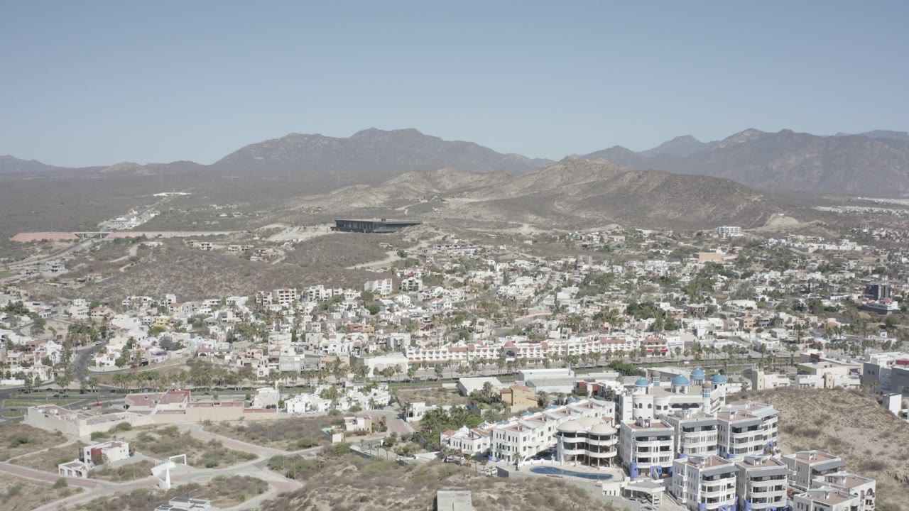 Aerial view over hillside villas and distant mountains.