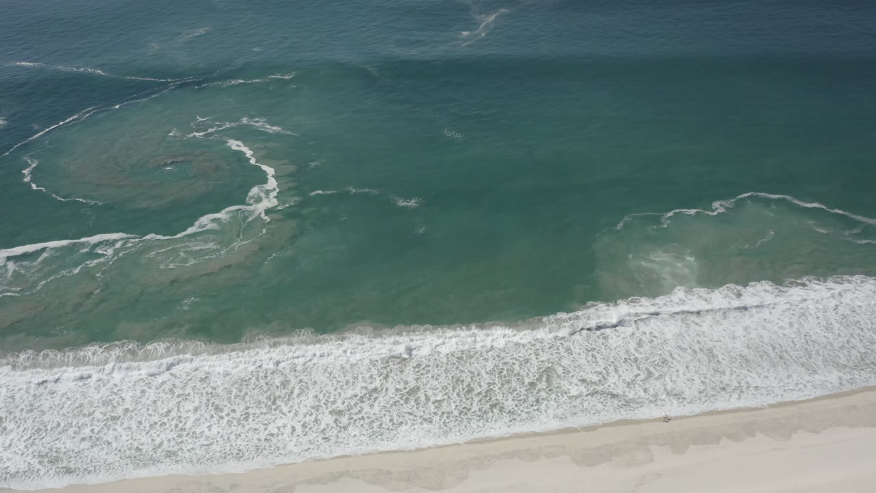 Curved foam trail over shallow green coastal water
