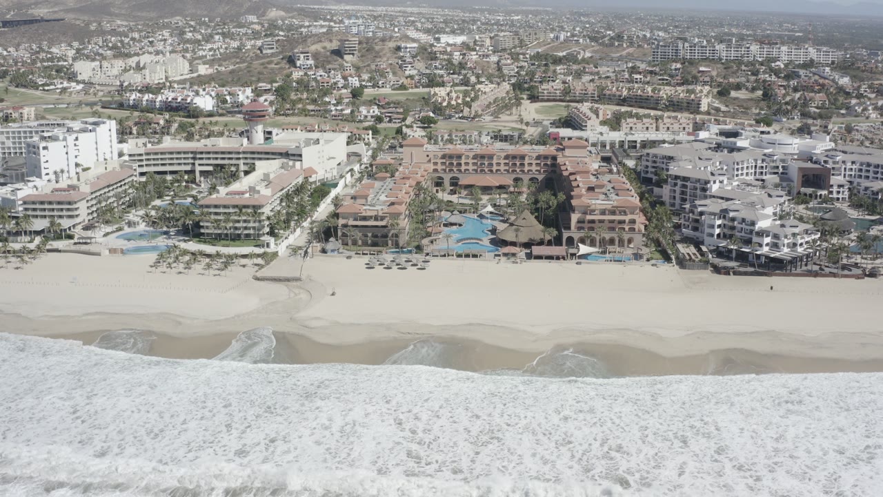 Beachfront apartments and hotels seen beyond surf and sand.