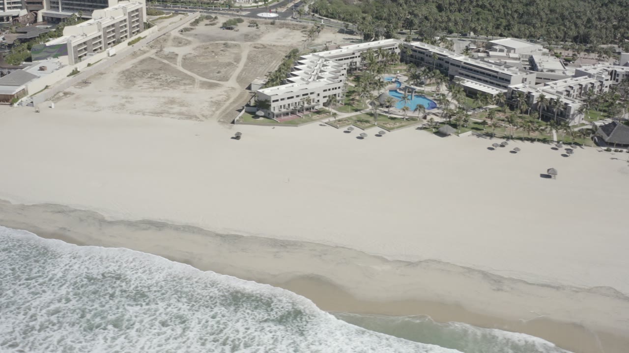 Beachfront complex with pools above a wide sandy beach.