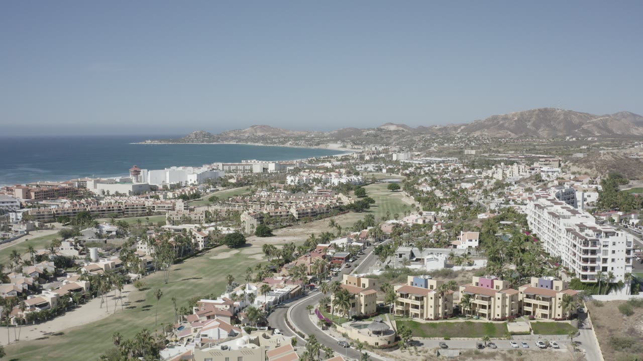Aerial view of coastal city, ocean, hotels, roads, and hills.
