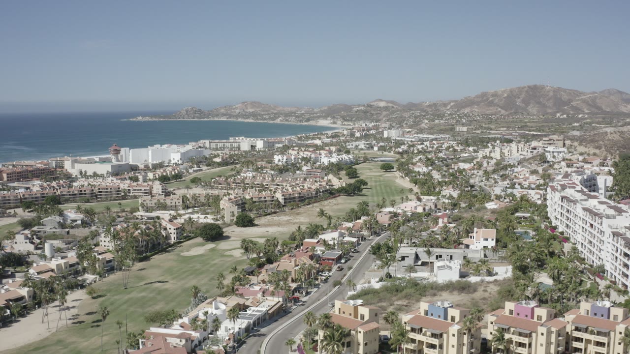 Aerial view of coastal houses, roads, sea, and mountains