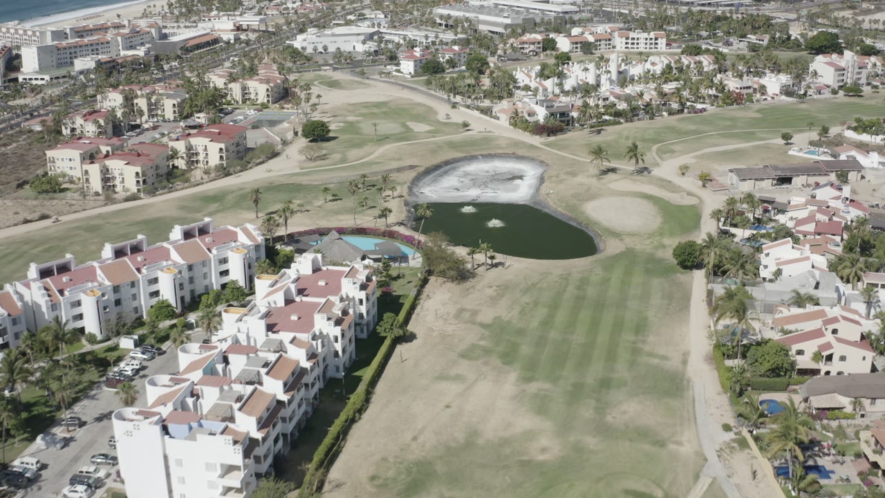 Aerial neighborhood view with golf green and pond.