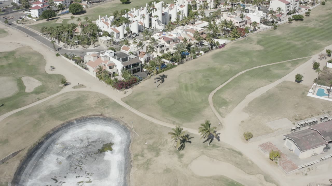 Overhead golf course paths and villas with a reflective pond