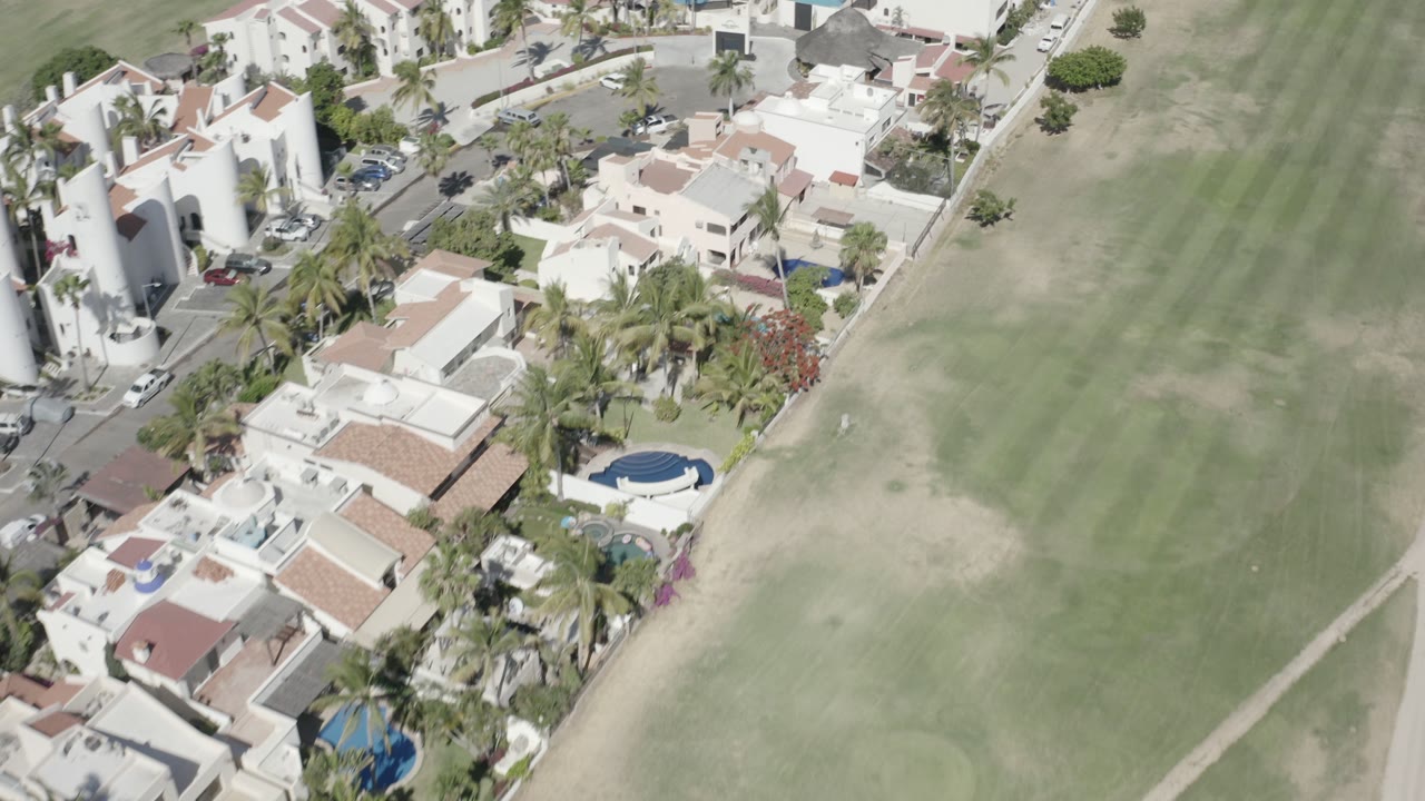 Aerial view of villas beside a striped grass clearing.