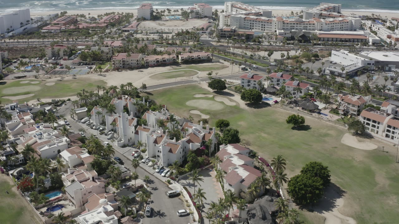 Aerial view over golf course, homes, beachfront hotels, and ocean