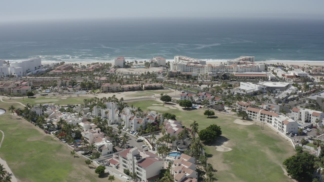 Aerial view of coastal buildings, golf course, beach, and ocean