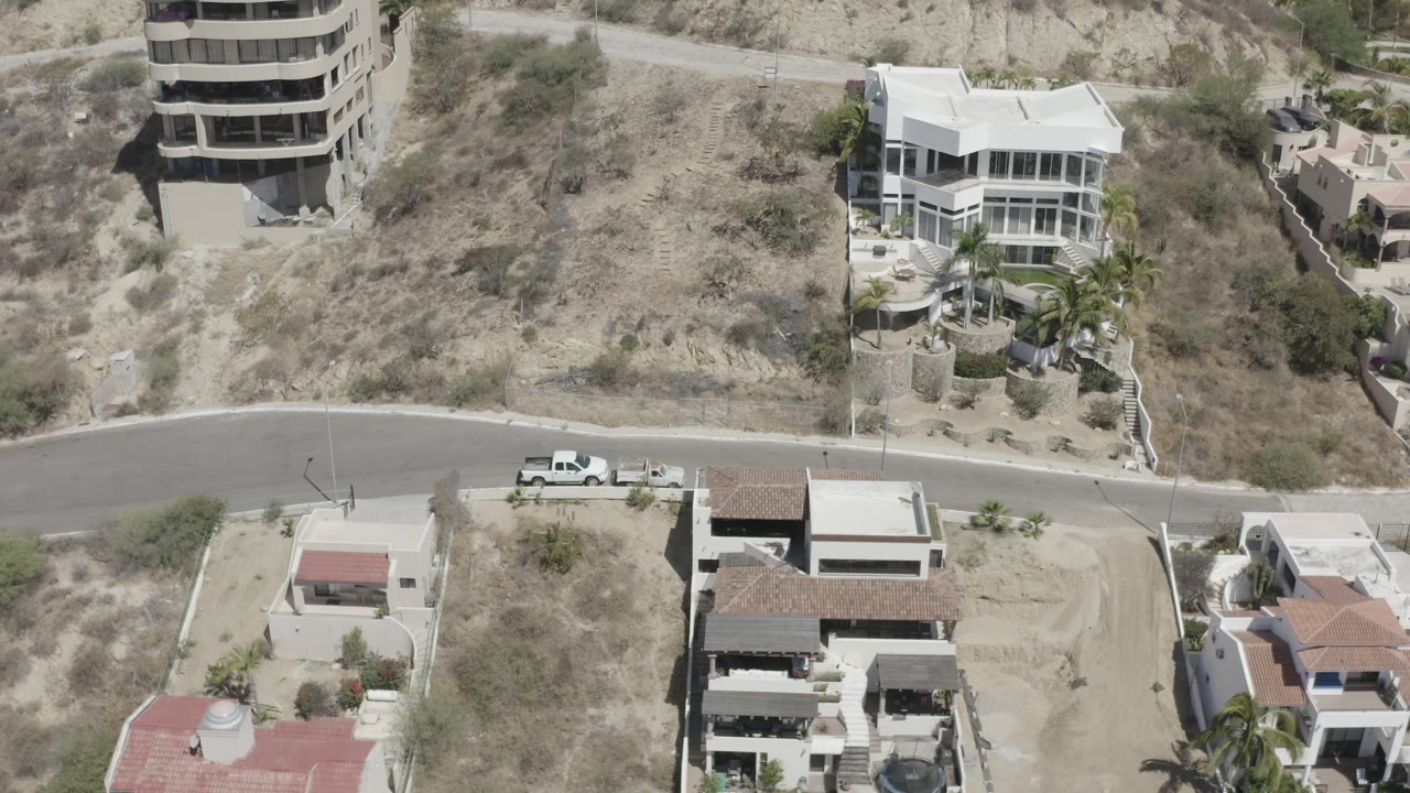 High overhead shot of hillside houses with dry brush and road.