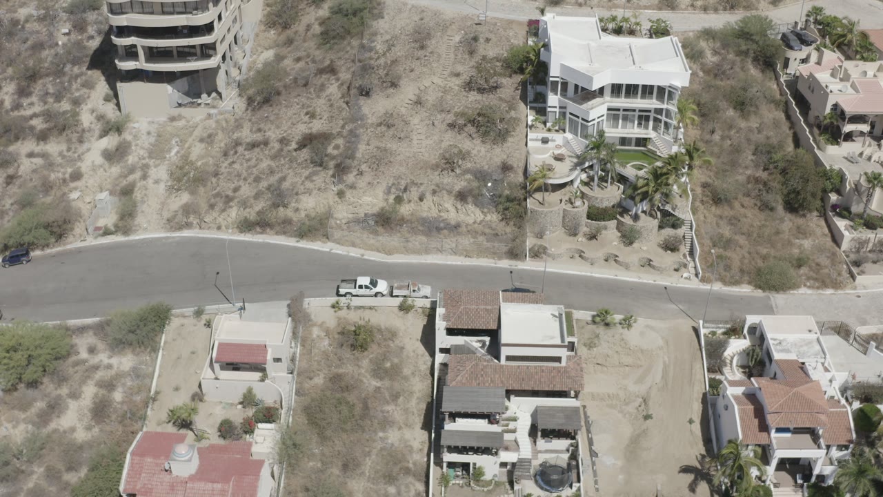 Top-down neighborhood road with parked white pickup and homes.