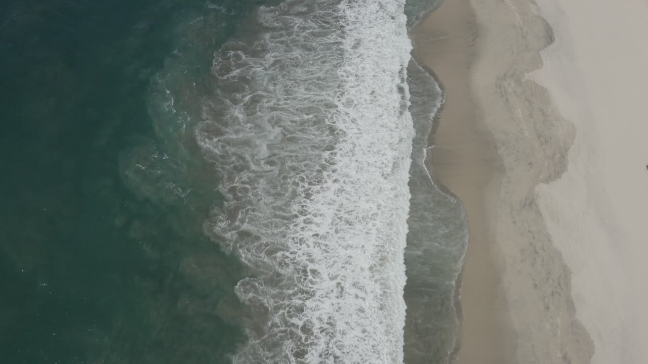 White surf curling across a sandy shoreline