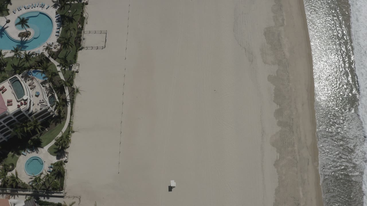 Open beach with surf and landscaped beachfront homes