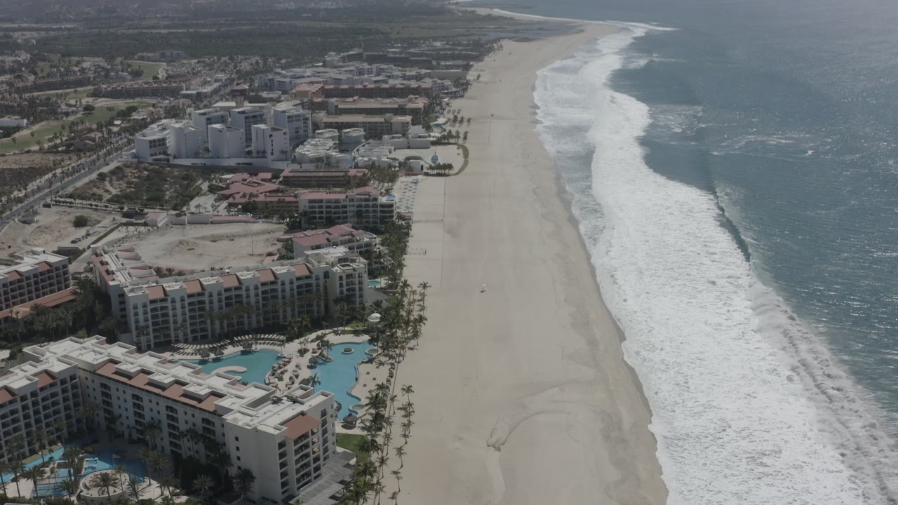 Coastal resort area viewed from above with ocean surf on the right.
