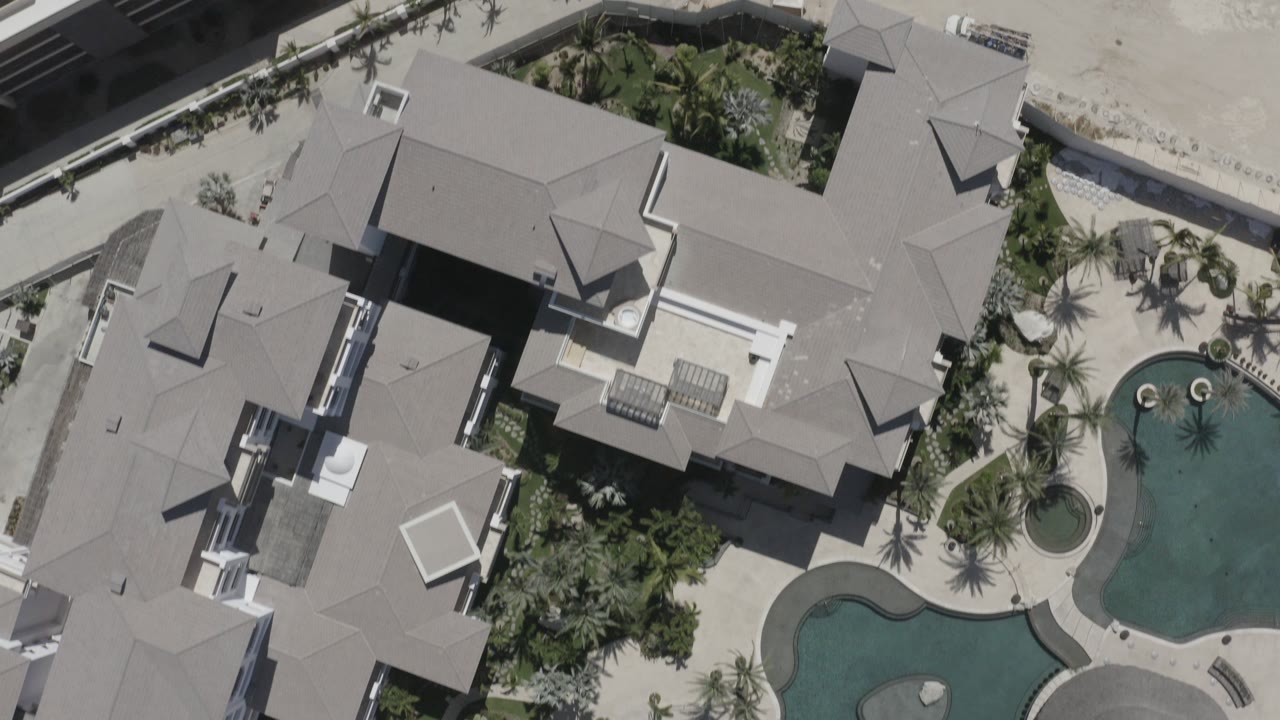 Overhead view of resort buildings and two curved pools.