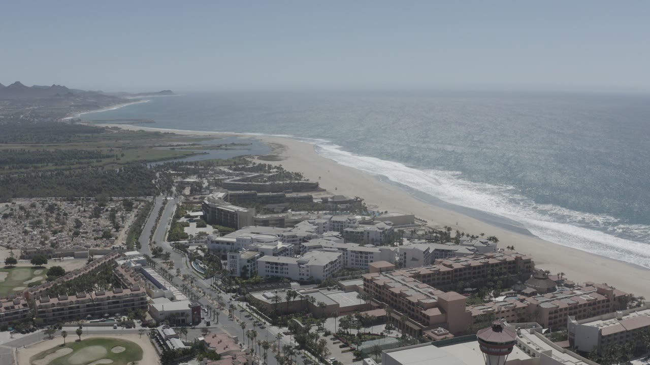 Wide aerial view of beach, city buildings, and ocean coastline.