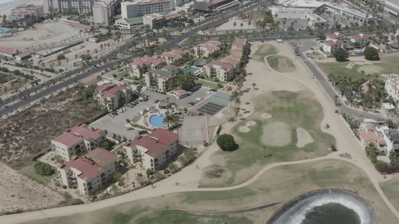 Aerial view of beachside housing beside a golf course and coastline.