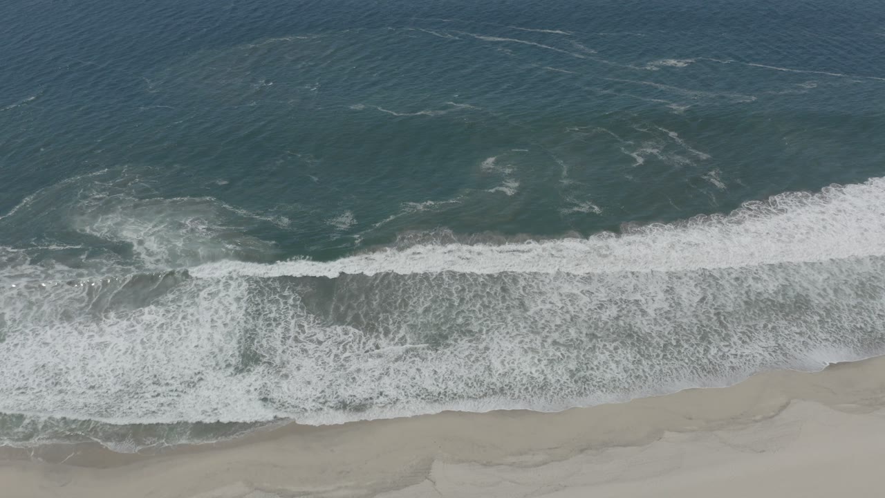 Blue ocean and broad white wave wash over sand