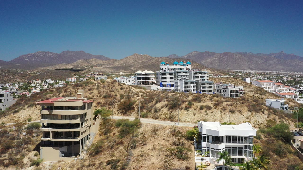 Aerial view of hillside homes, dry terrain, city blocks, and mountains