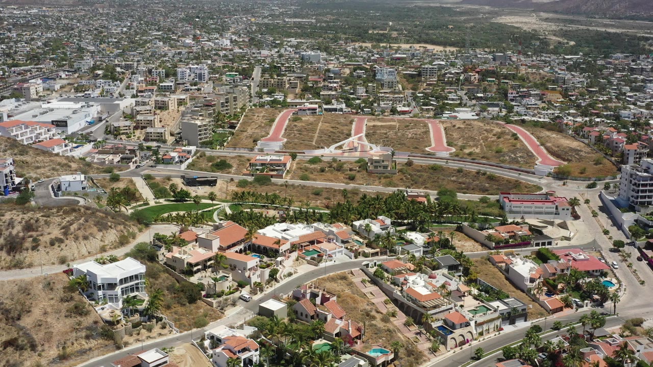 Residential hillside with red paths and a sprawling town beyond.
