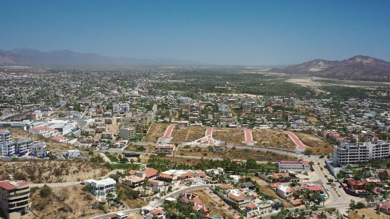Aerial view over a sunlit city with hills and mountains