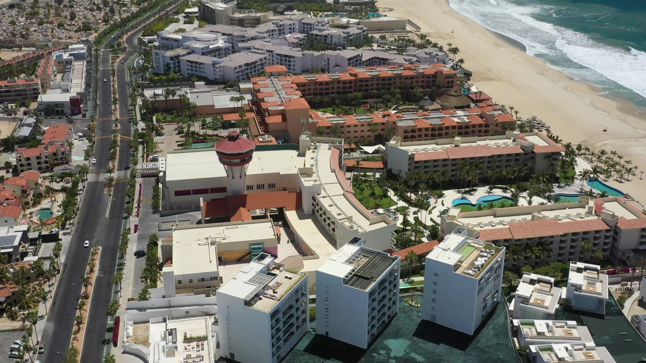 High drone angle over hotels, pools, road, beach, and ocean