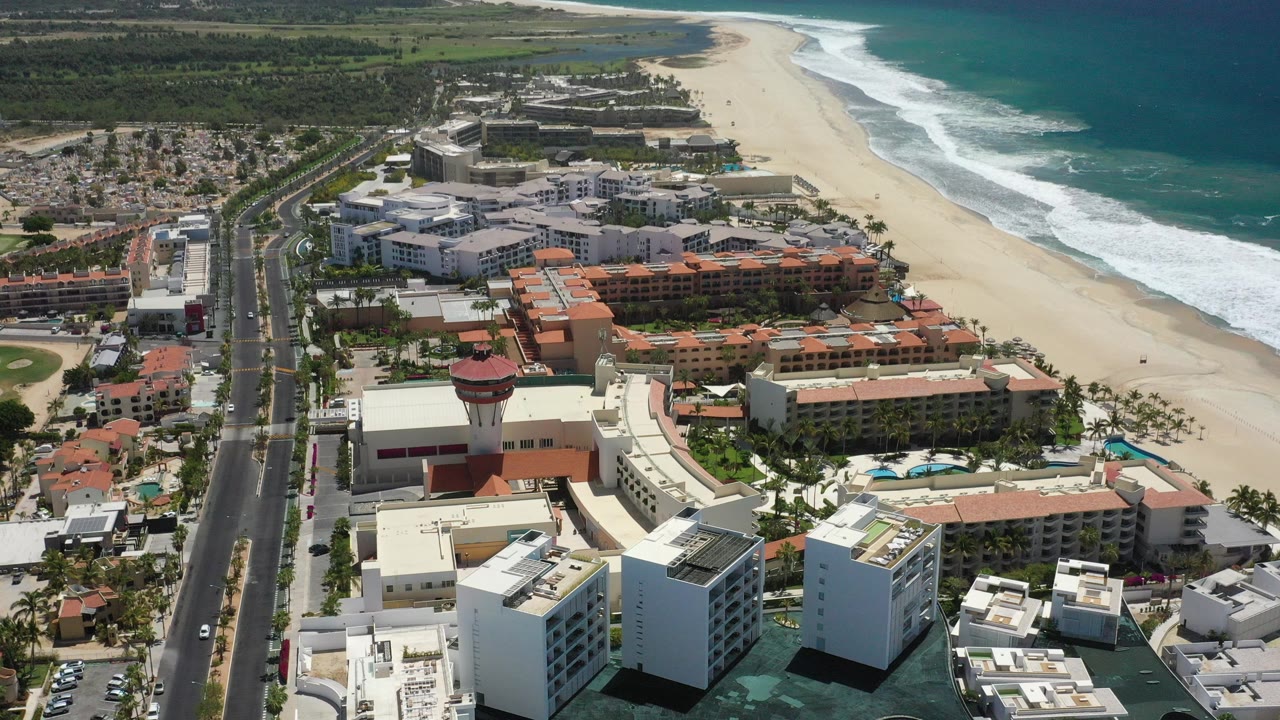 Aerial view of beachfront buildings, road, sand, and surf