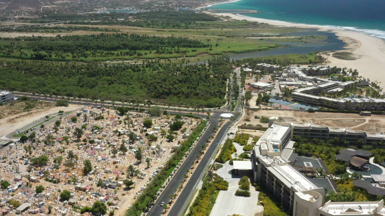 Aerial view of a road, buildings, green wetlands, sand beach, and ocean.