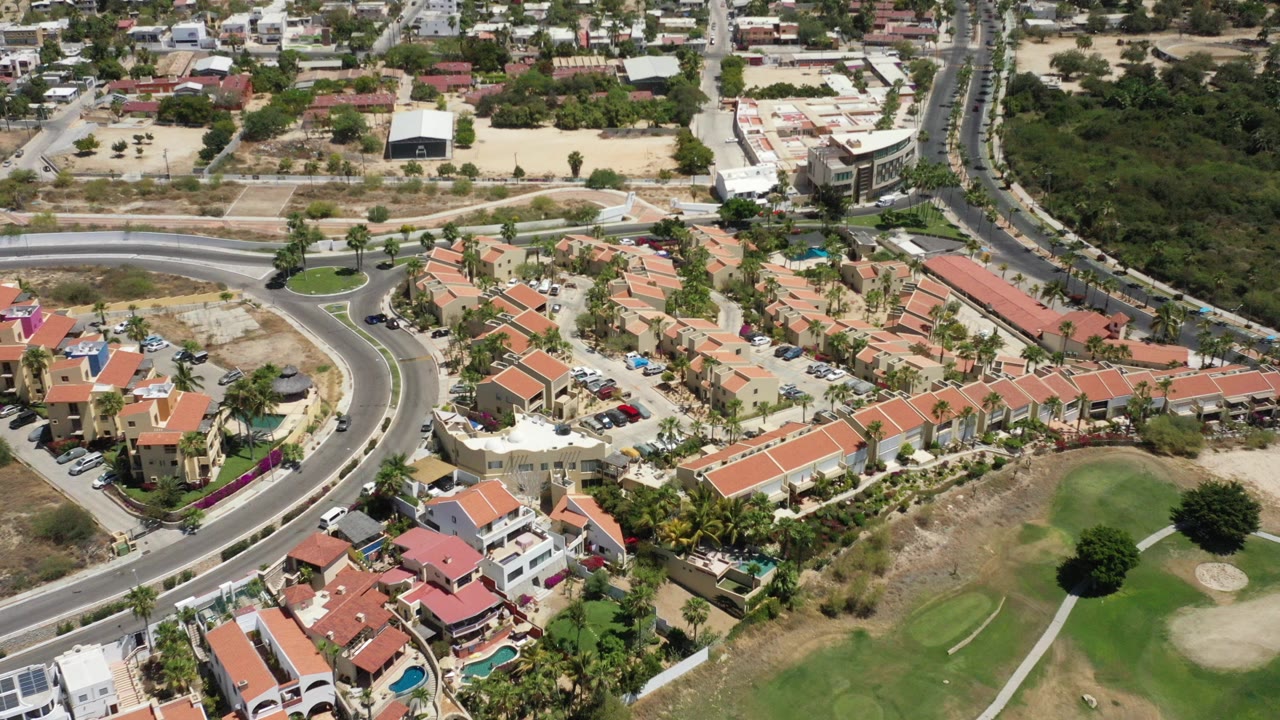 Aerial view of terracotta-roofed homes beside curved roads and golf-course grass.