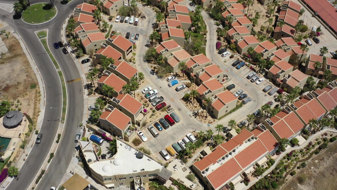 Overhead view of apartment buildings, parking lots, and a curved road.