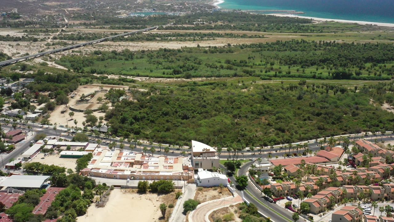 Aerial view of town, green trees, roads, mountains, and ocean horizon.