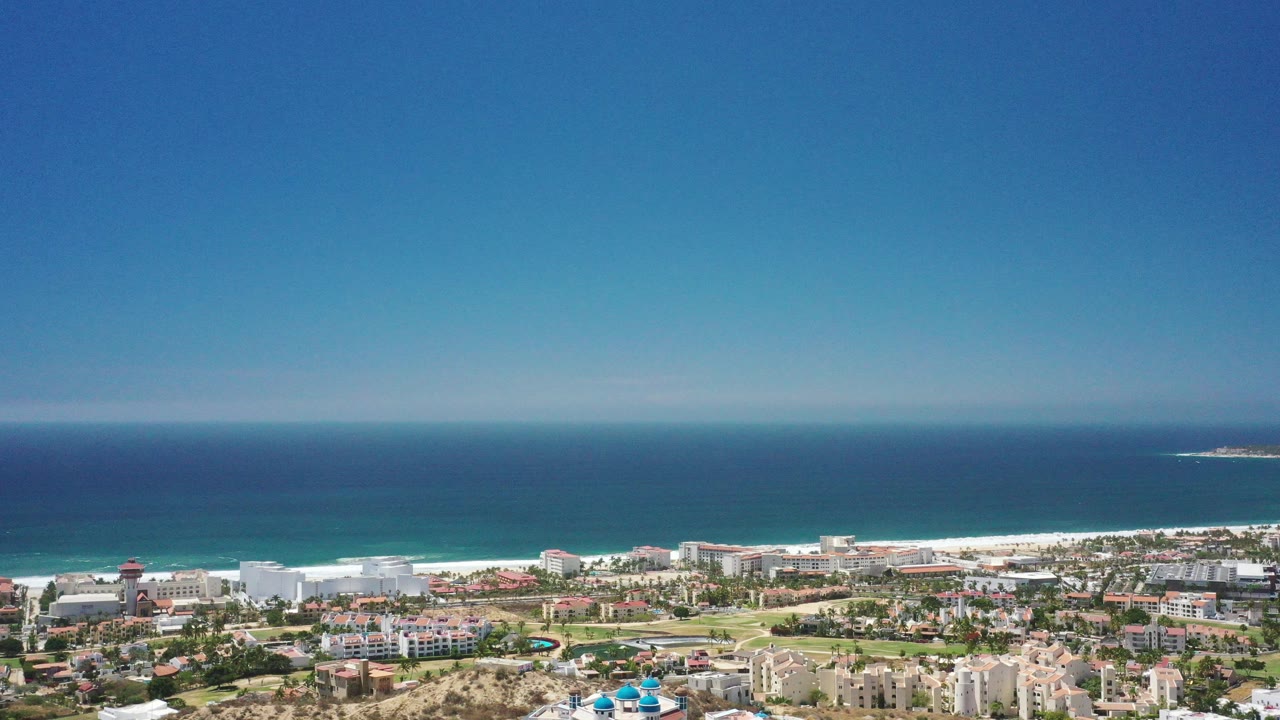 Wide aerial view of coastal city, beach, and blue ocean.