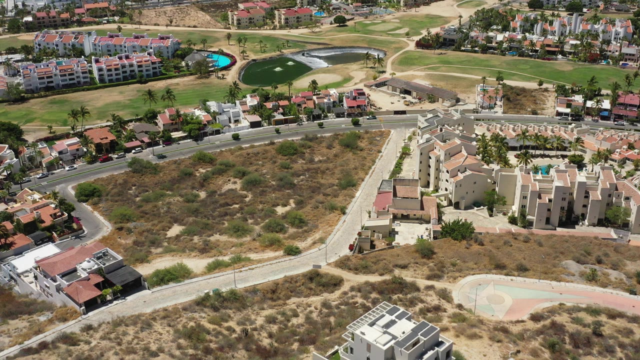 Overhead view of resort buildings, roads, dry scrubland, pools, and golf greens.