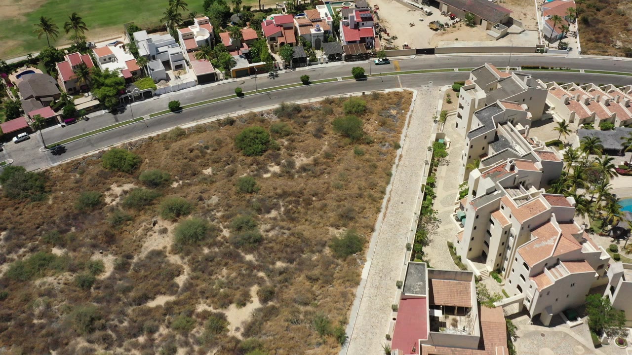Aerial view of a curved road beside dry lots and residential buildings.