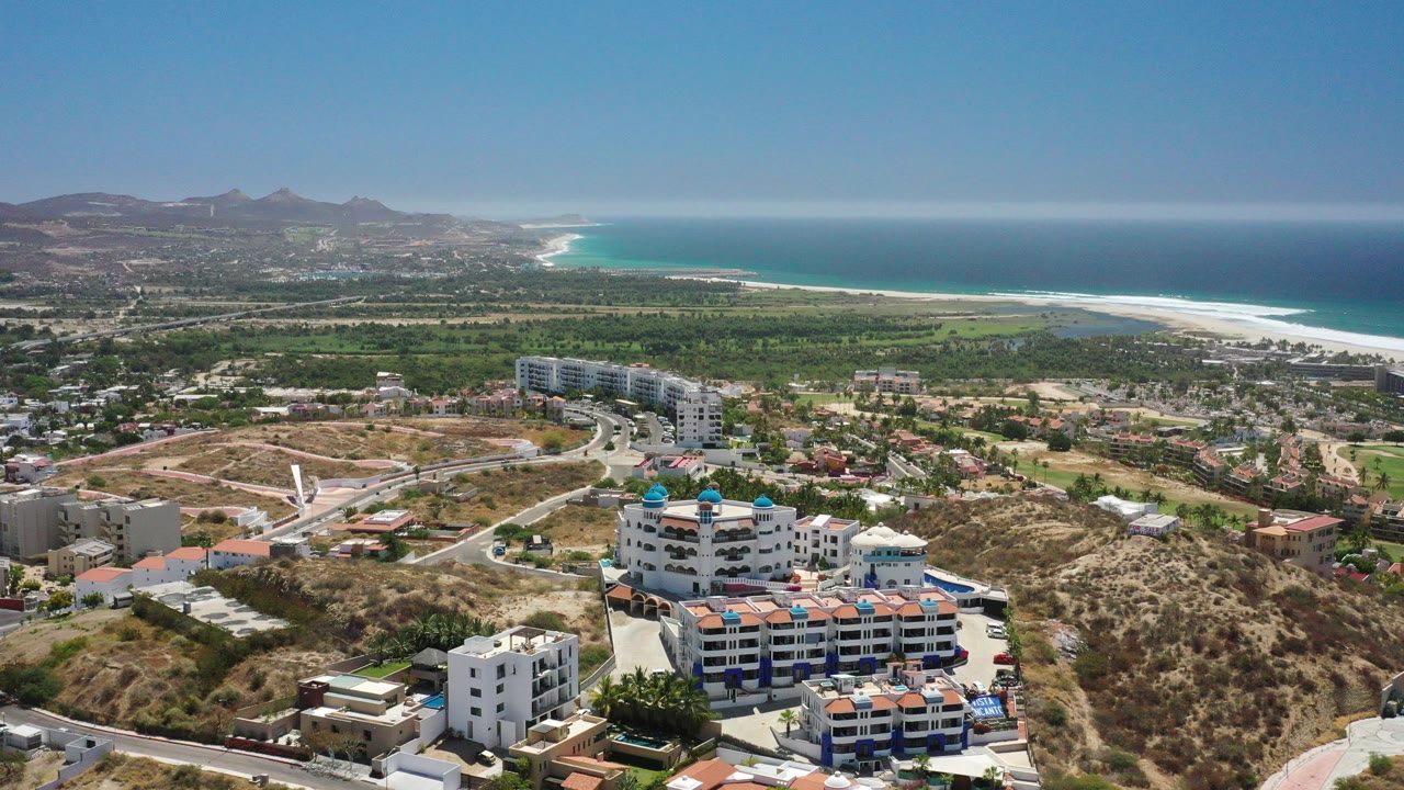 Aerial view of resort buildings, hills, vegetation, beach, and ocean
