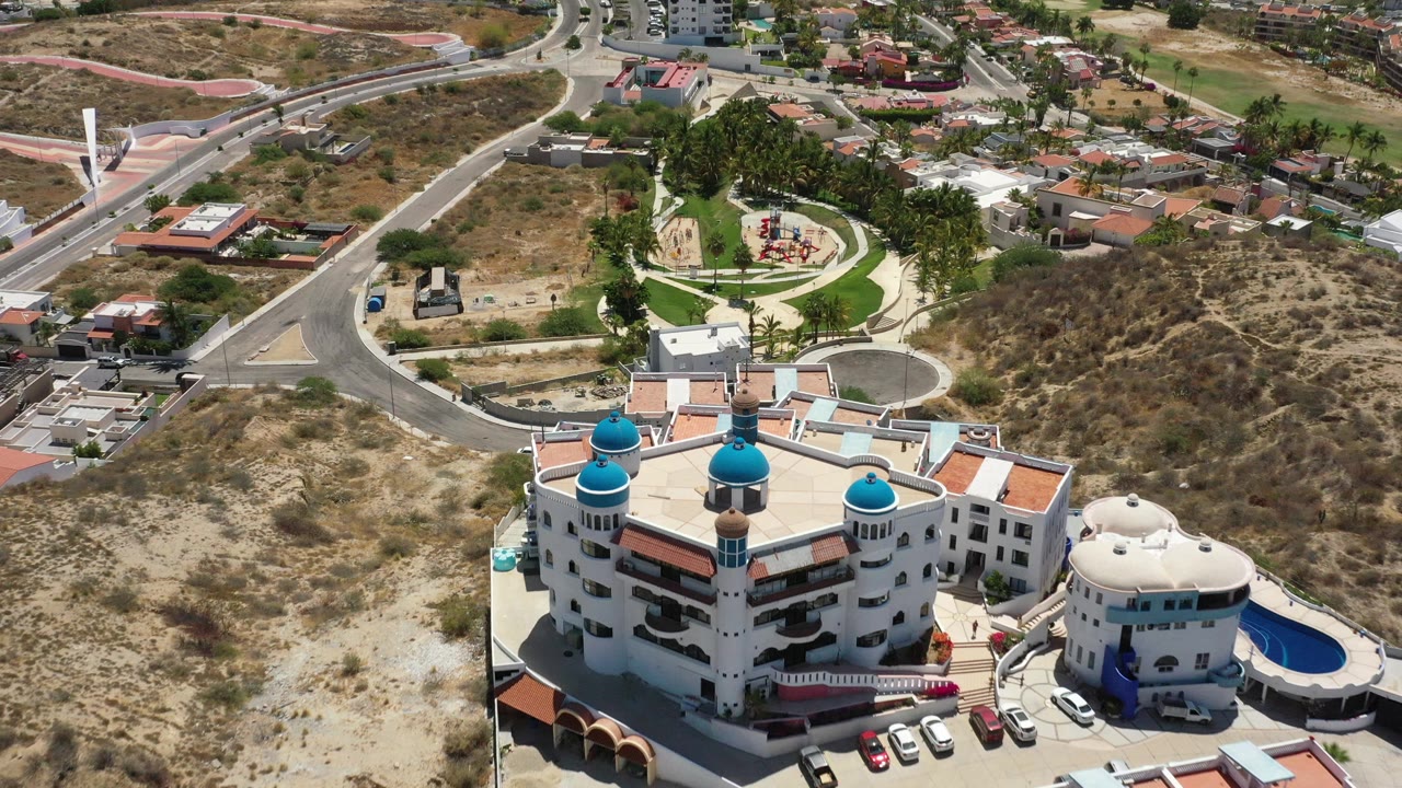 White domed resort beside a curved pool with dry terrain and roads beyond.