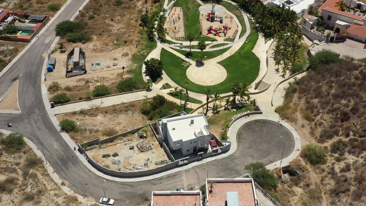 Overhead drone view of a small park, roads, homes, and dry lots.