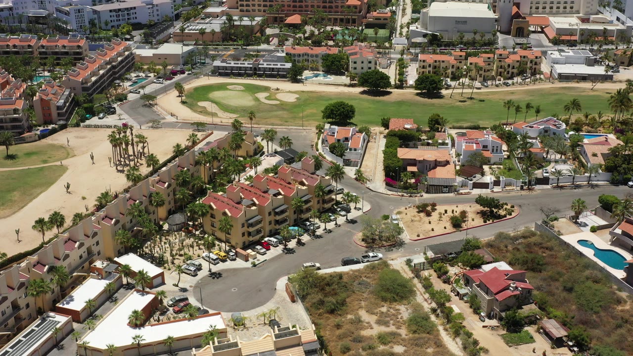 Third frame shows the San Jose del Cabo city blocks from above, with resort-style buildings at the top, a green course through the middle, and homes, palms, parked cars, and pools below, with no visible people.