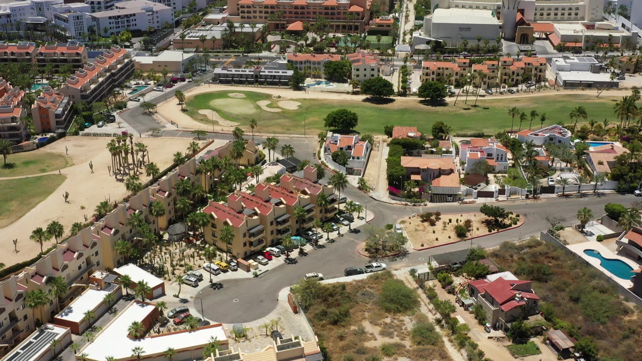 Aerial view of resort buildings, roads, palms, beach, and ocean.