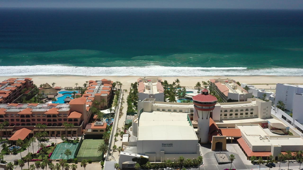 Aerial view of beachfront resort buildings beside a turquoise ocean.
