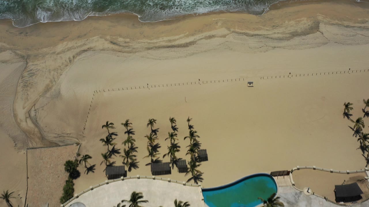 Beach sand with palms and pool edge from above