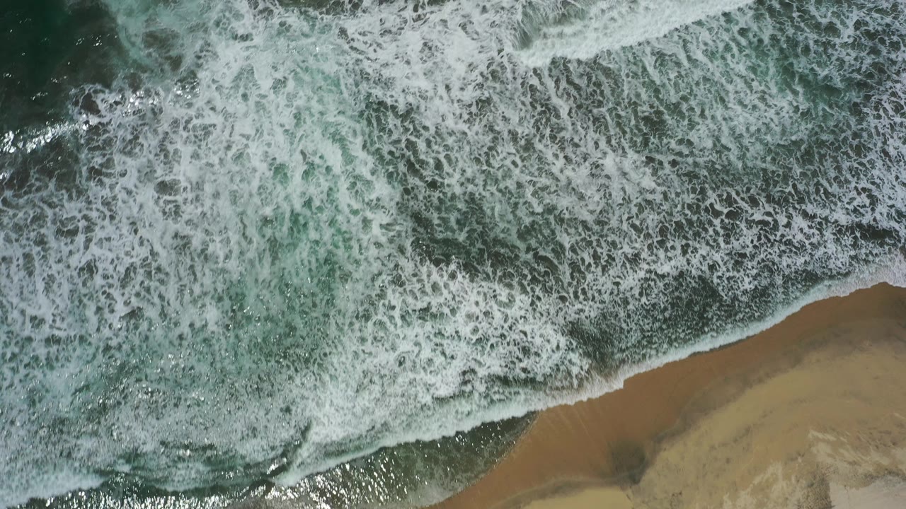 Dense ocean foam over shoreline water