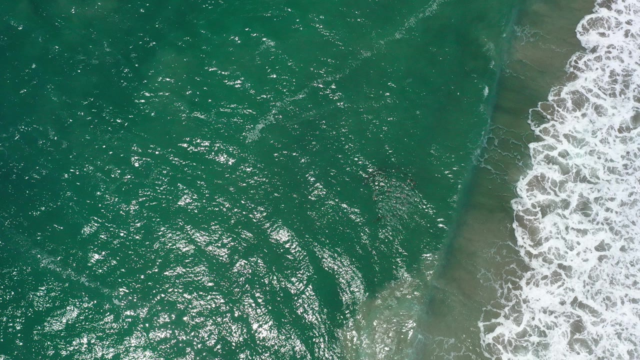 Overhead turquoise ocean with white surf breaking diagonally