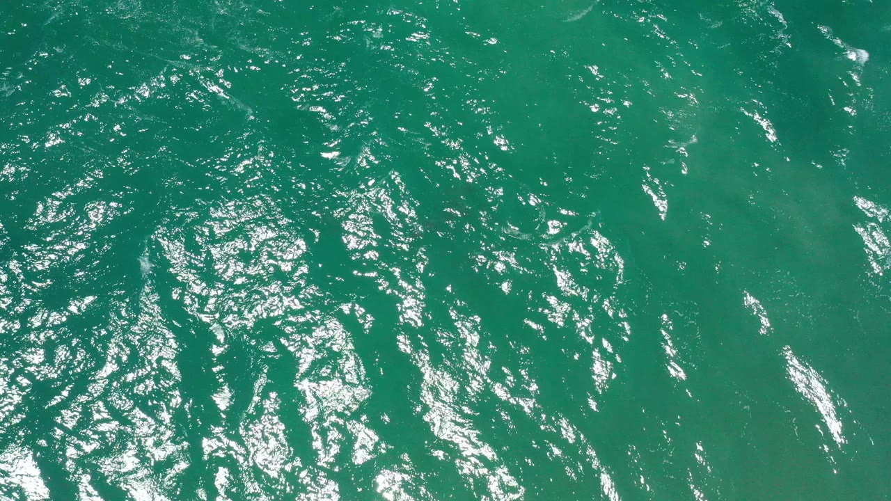 Green sea surface with bright reflected streaks.