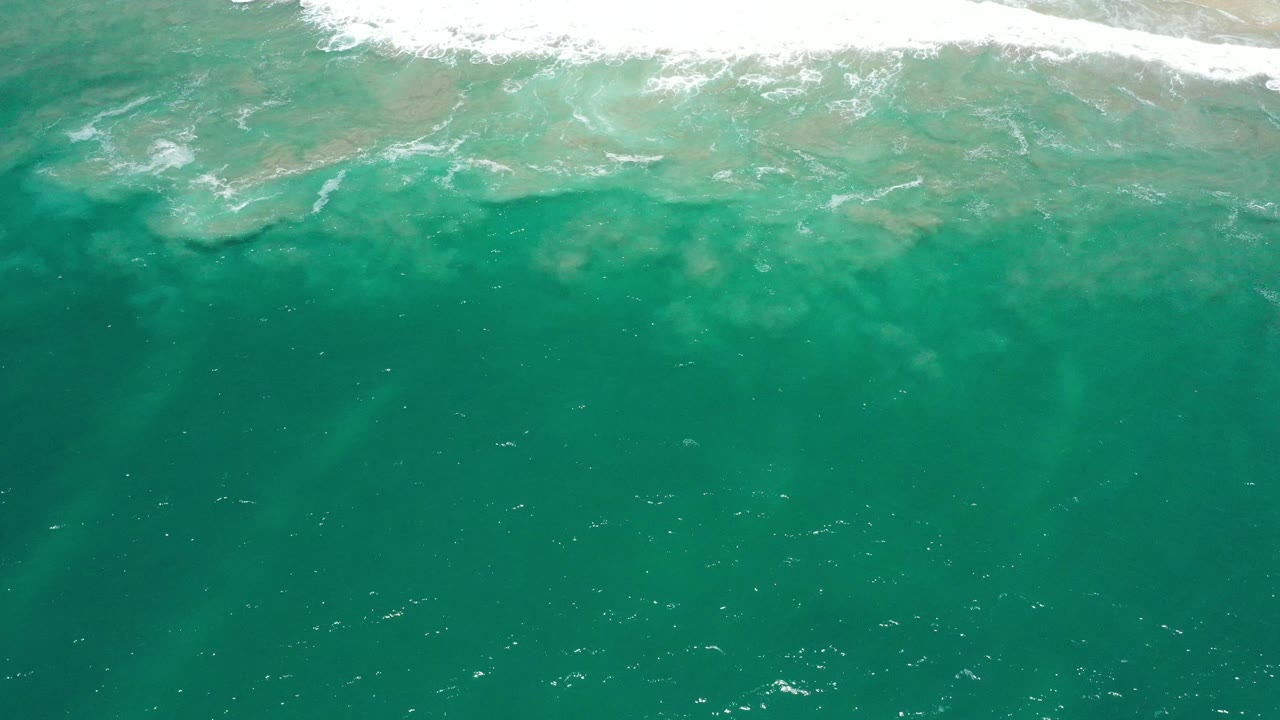 Aerial ocean surface with bright foam and clear green water