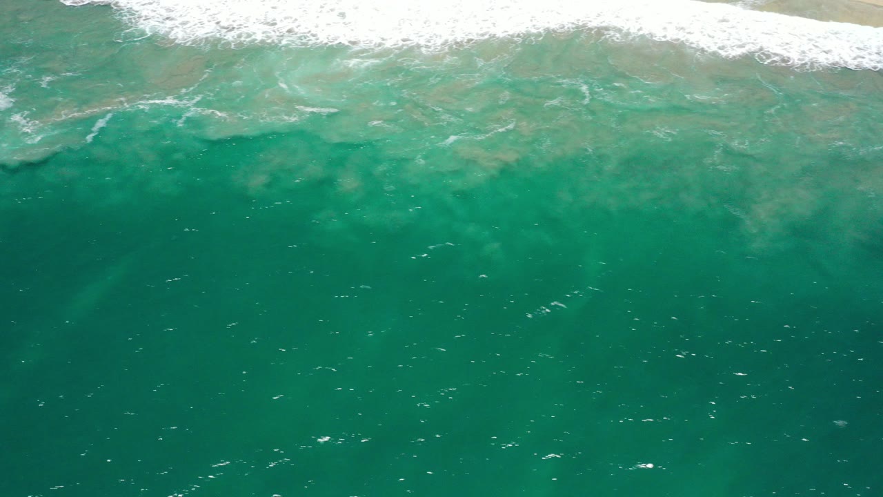 Aerial view of turquoise water off San Jose del Cabo with a band of white surf at the top edge and no visible people.