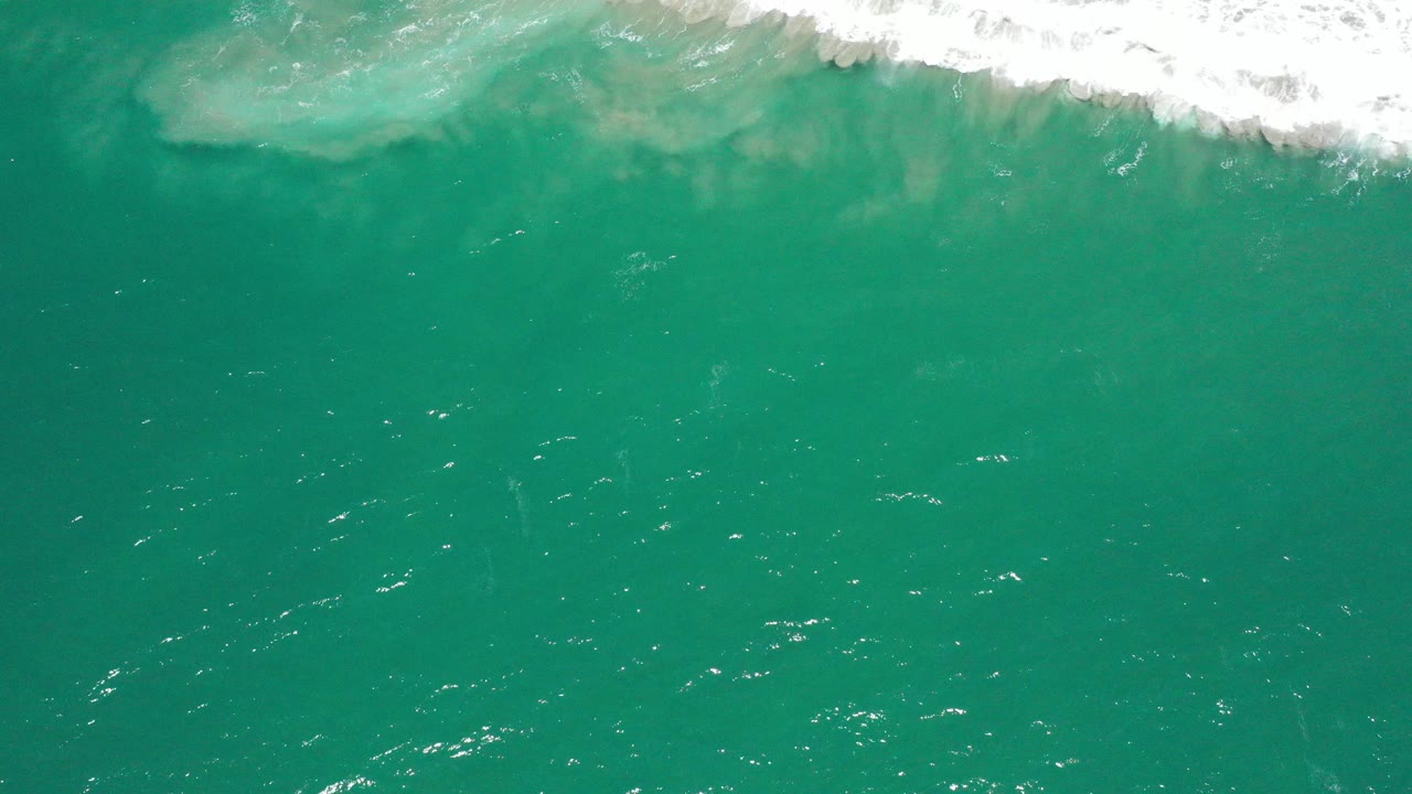 Overhead blue-green ocean with white surf along the top edge.