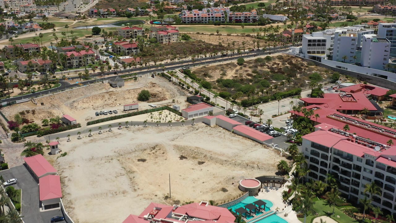Elevated view of red-roofed buildings, dry lots, roads, and white apartment blocks.